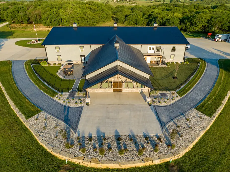 Aerial view of a large Kansas property with a paver driveway and a circular landscape bed set into new turf
