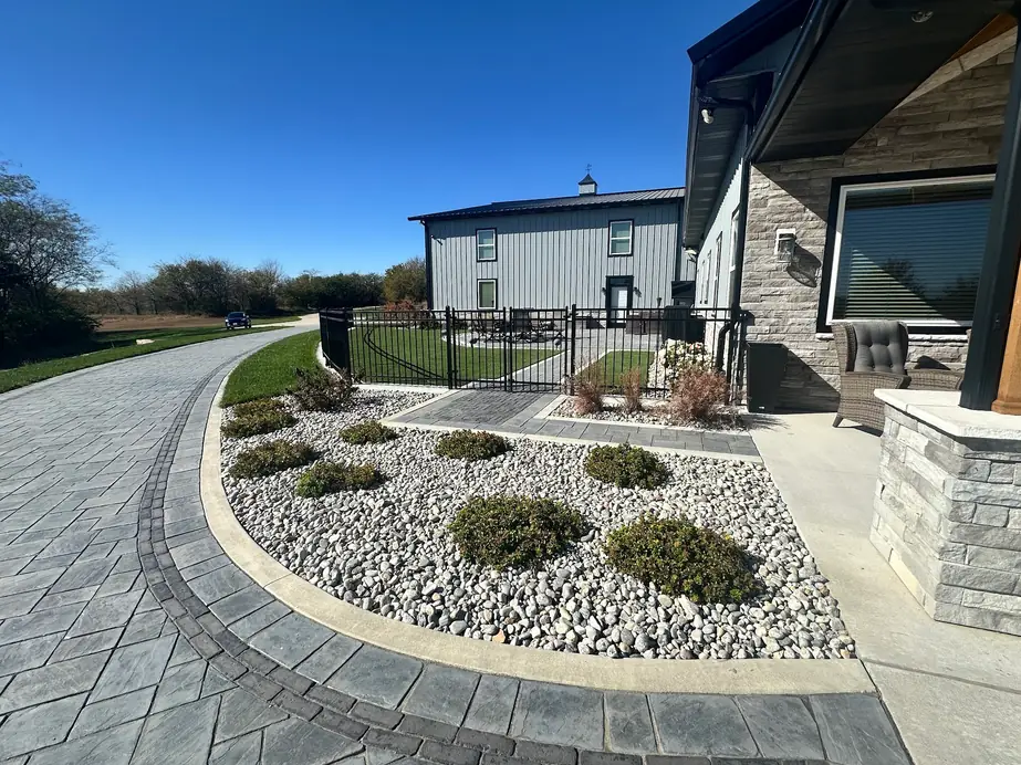 Finished paver driveway edged with a river rock foundation bed running along a large home
